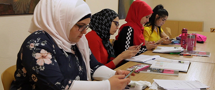 Vier Frauen lernen mit Smartphones an einem Tisch mit Büchern und Heften, Foto: Bildungsfilm