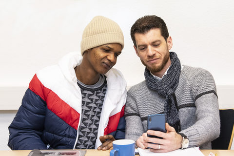 Zwei Männer schauen gemeinsam auf ein Smartphone